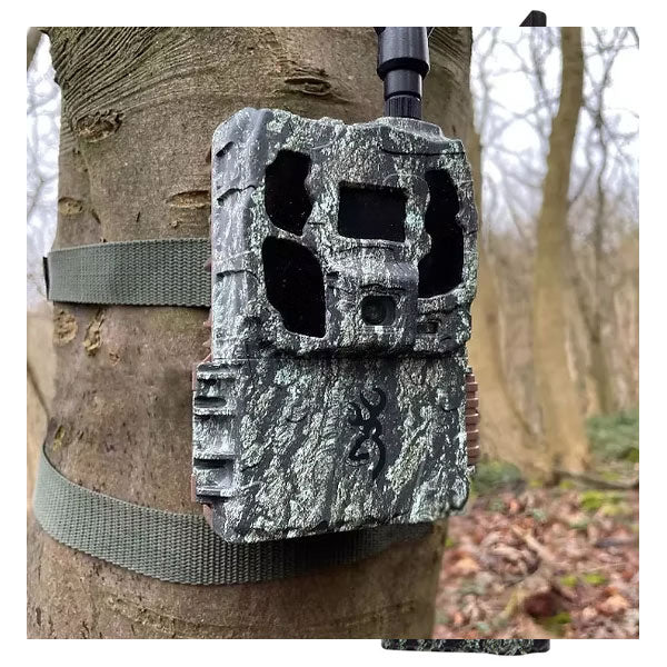 Defender pro scout solar Game camera attached to a tree in a forest setting.
